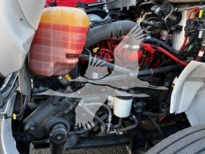 Truck engine bay showing coolant reservoir, hoses, and various engine components.