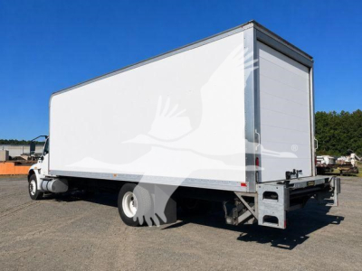Box truck with a large white cargo box and chassis visible, rear view shows roll-up door and taillights.