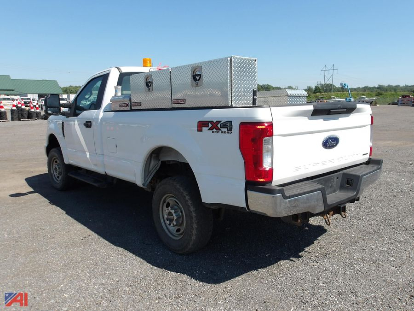 Ford F-250 Super Duty pickup truck in white with FX4 off-road package badge, aluminum toolbox on bed, viewed from rear-left side.