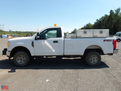 Side view of a white 2019 Ford F-250 Super Duty pickup truck with utility bed, single cab, long wheelbase, orange beacon on cab roof, and FX4 badge.