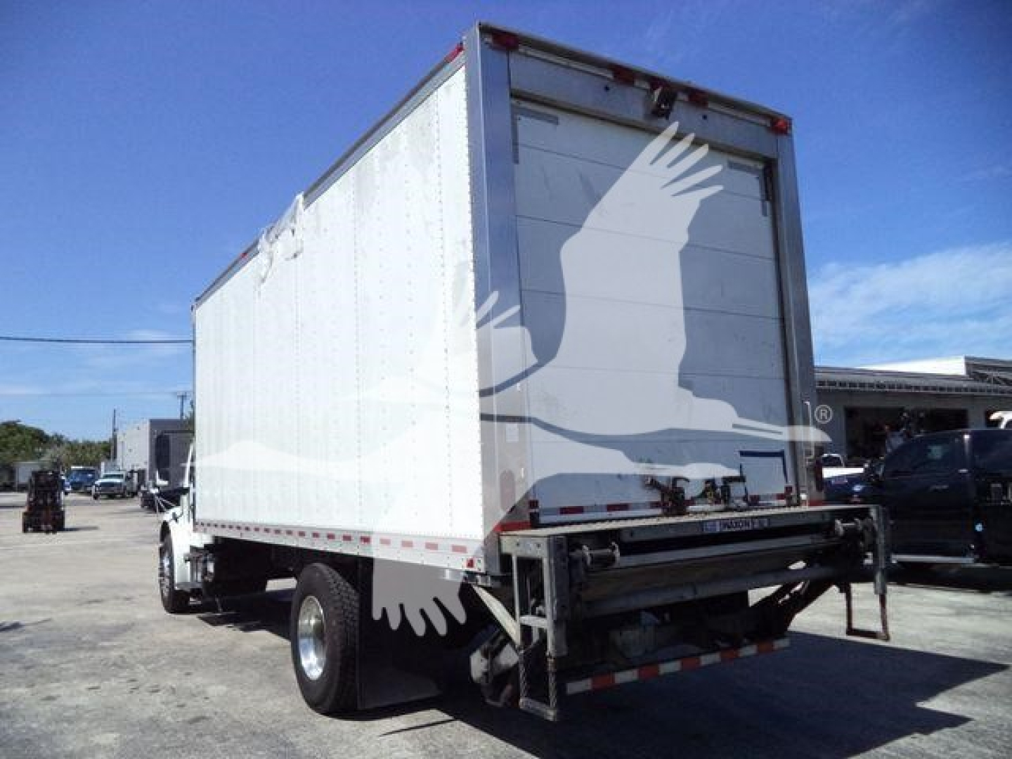 Rear and passenger-side view of a 2019 Freightliner M2 106 refrigerated truck with a white box body. Visible rear doors and underride guard.