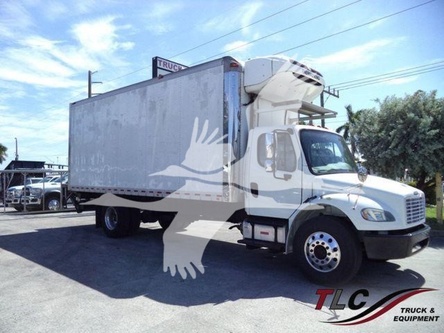 Freightliner M2 106 refrigerated truck side view showing cargo box and cab with front wheel and logo.