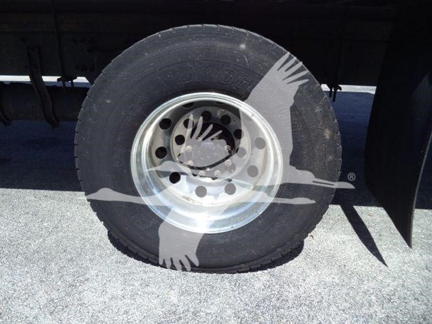Wheel of a Freightliner M2 106 refrigeration truck showing steel rim, black tire, and wheel well.