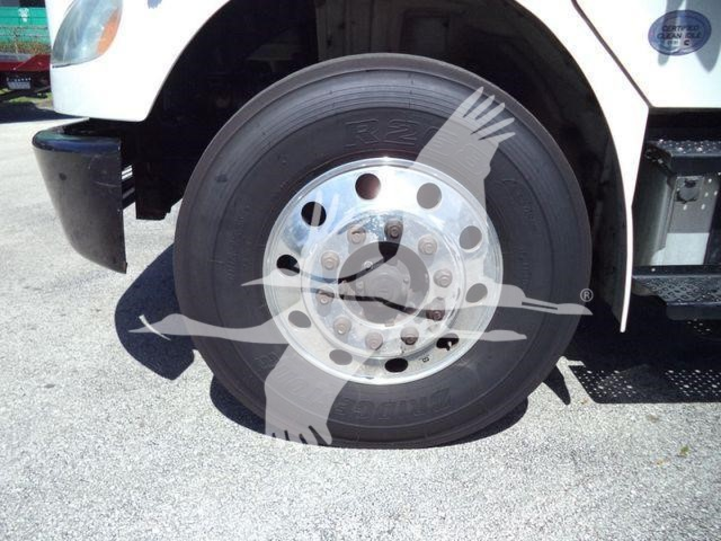 Truck wheel and front fender of a Freightliner M2 106 refrigeration unit, with wheel hub and tire details visible.