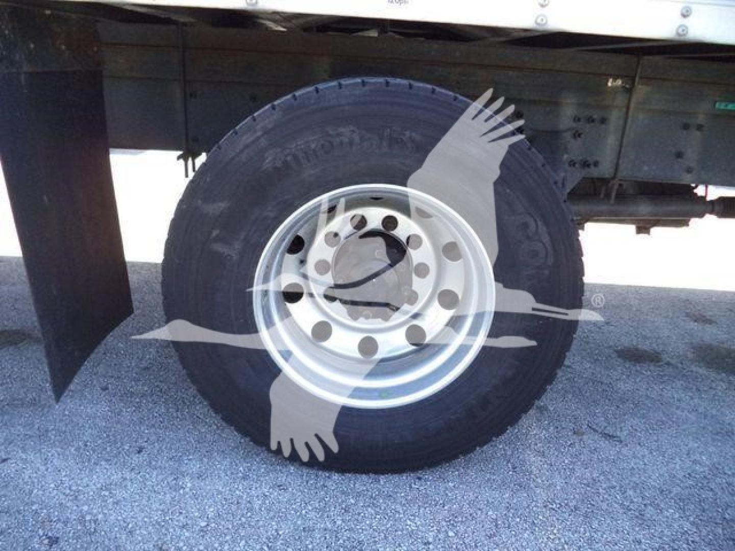 Wheel and tire of a Freightliner M2 106 truck showing steel rim and tire tread, with part of the undercarriage/drive area visible.