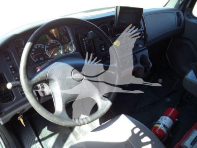 Cab interior of a Freightliner M2 106 truck showing steering wheel, dashboard, and a mounted tablet; a fire extinguisher lies on the floor.