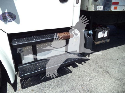 Step/footboard area of a 2019 Freightliner M2 106 truck showing rubberized steps and a side battery box with battery visible; partial front door with inspection badge.