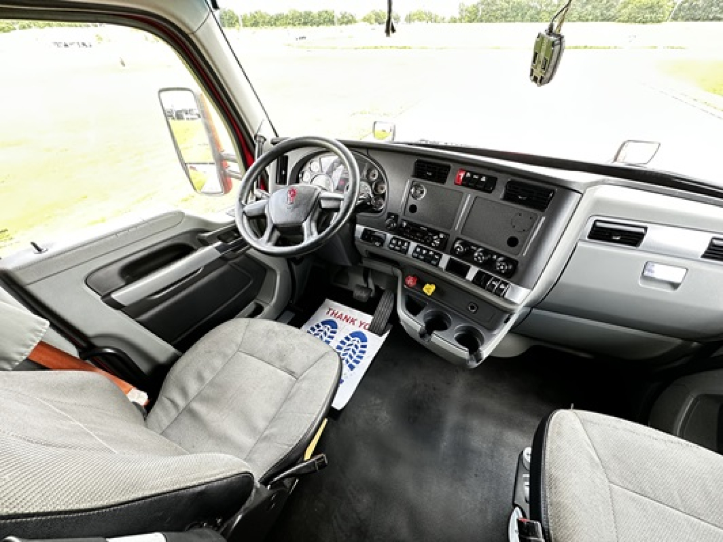 Kenworth T680 truck interior showing steering wheel, dashboard, and front seats with center console and controls.
