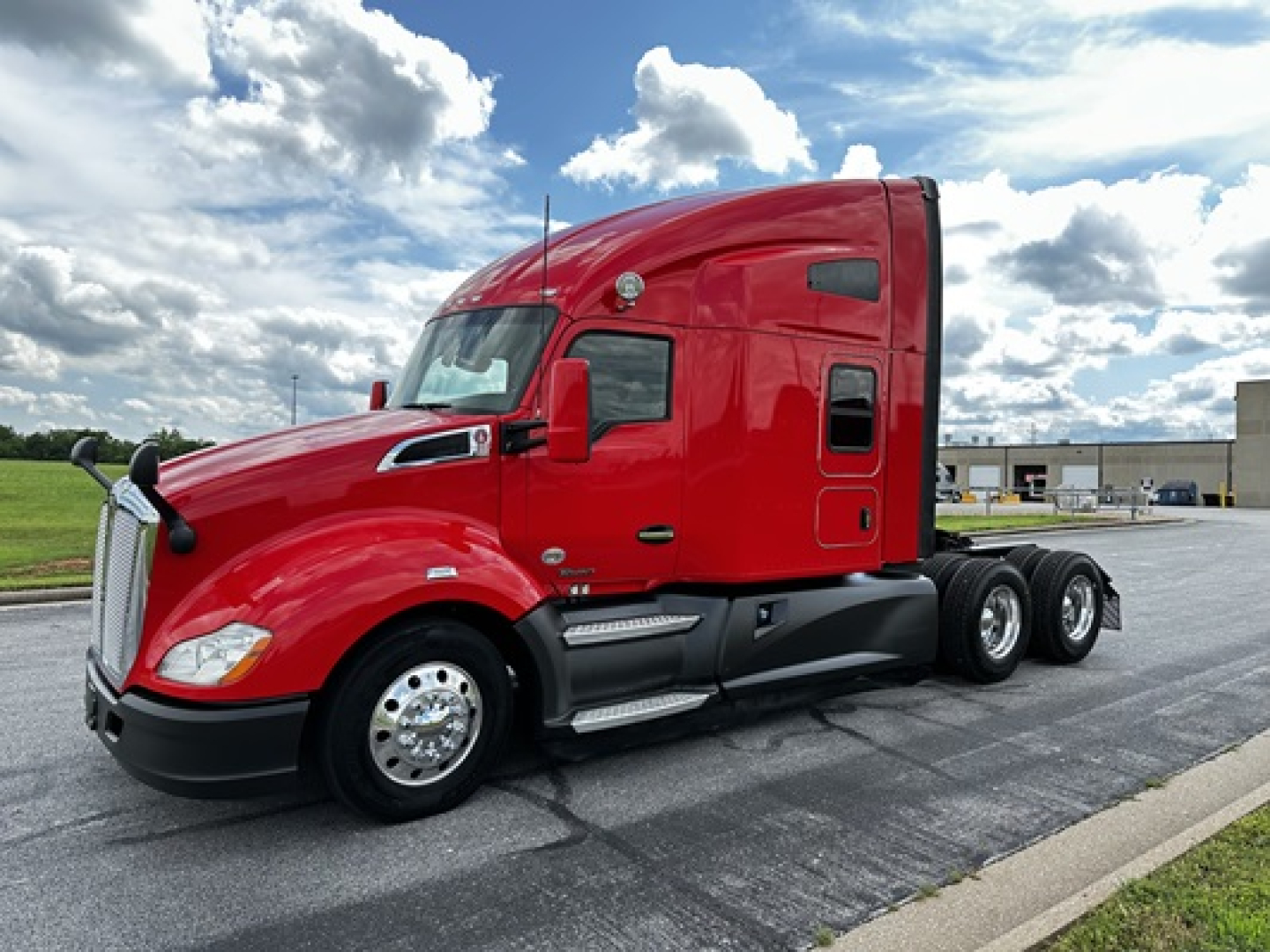 Truck side view showing a red 2022 Kenworth T680 sleeper cab with three axles, chrome wheels, and black lower trim.