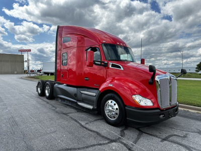 Kenworth T680 2022 conventional sleeper tractor in red, side view with triple rear axles, chrome grille, black bumper, on pavement.