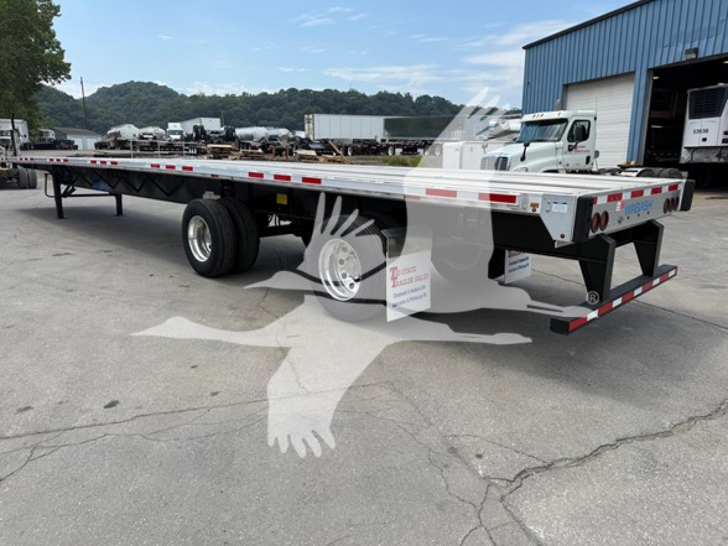 Flatbed trailer with rear axle slide showing aluminum deck, dual rear axles, and reflective safety stripes. VIN decal and stock number SC447895 visible near front.