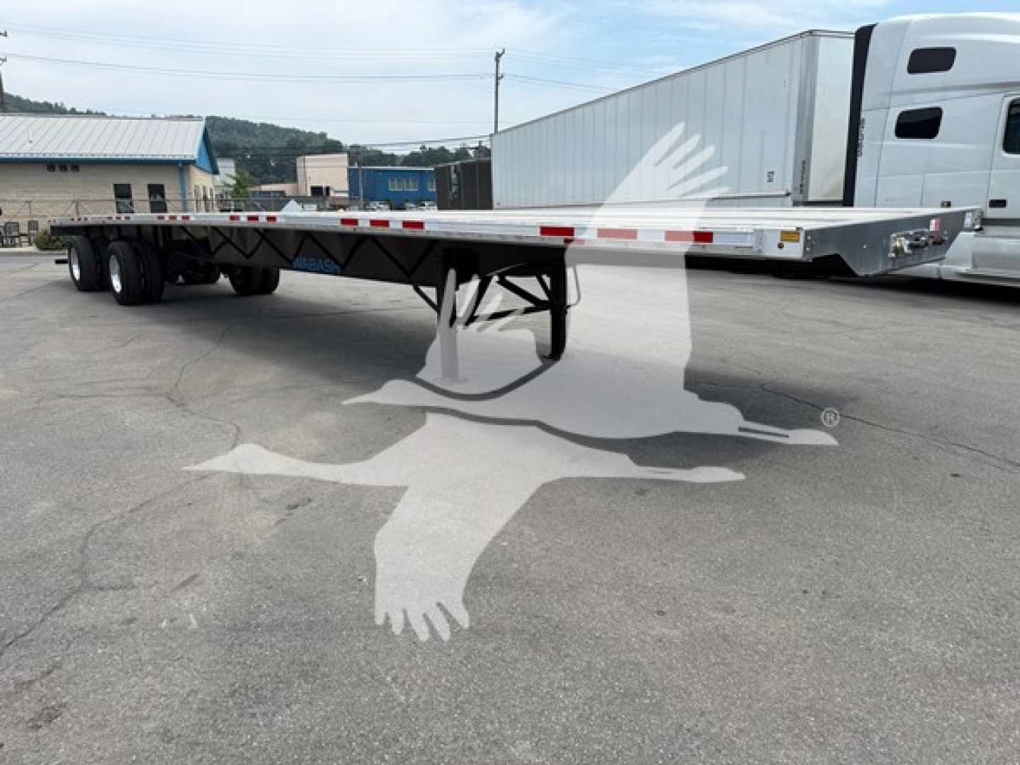Trailer flatbed with rear axle slide showing long aluminum deck and multiple axles, no visible branding text.