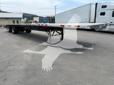 Trailer flatbed with rear axle slide showing long aluminum deck and multiple axles, no visible branding text.