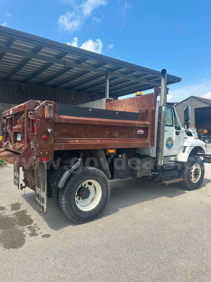 Dump truck 2008 International 7400 side rear showing brown dump bed and white cab with black exhaust stack.