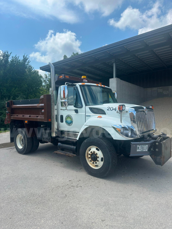 Dump truck in service with white cab, dump bed, and front bumper damage plate. Visible text includes International logo on grille and stock number 5750-254.