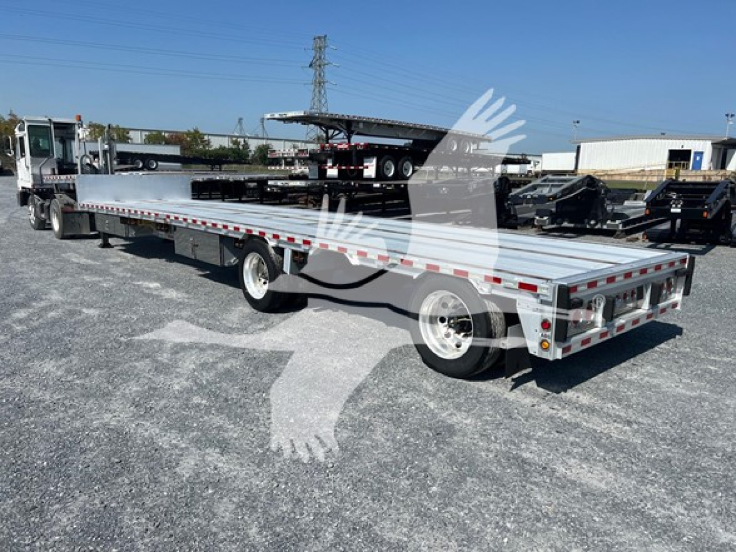 Used 2018 Reitnouer drop deck trailer in a lot, side view showing flatbed with dual rear wheels and reflective tape.