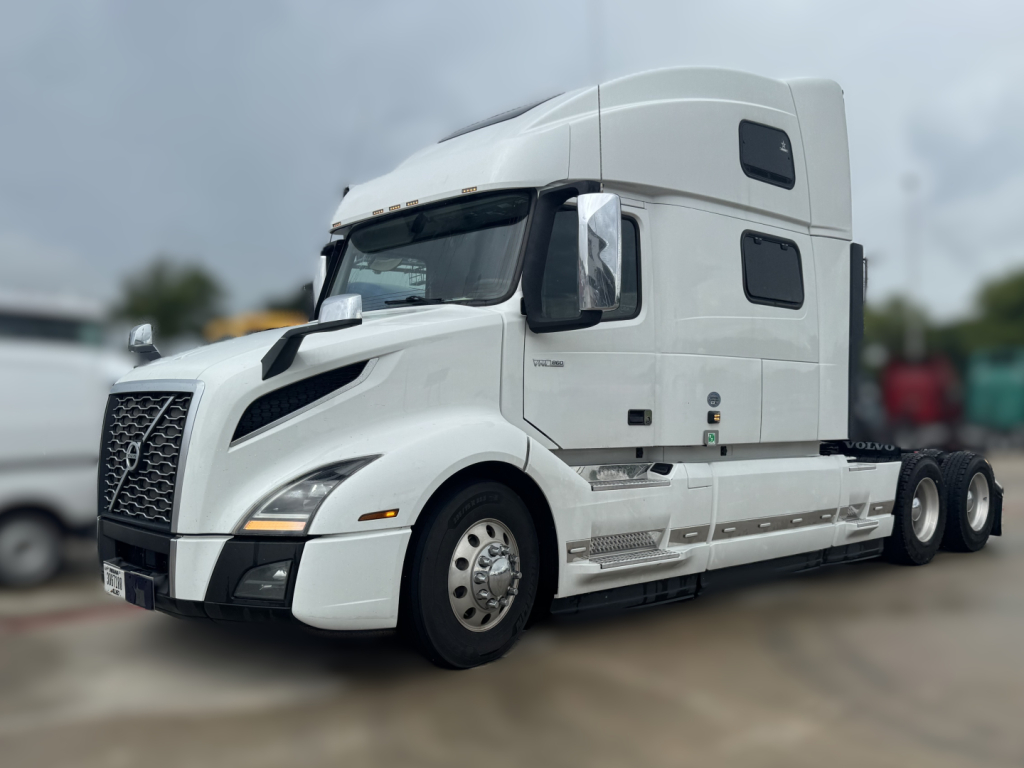 Volvo VNL64T860 tractor-trailer in white, cab view showing sleeper, side steps, dual rear axles, and Volvo badge on grille.