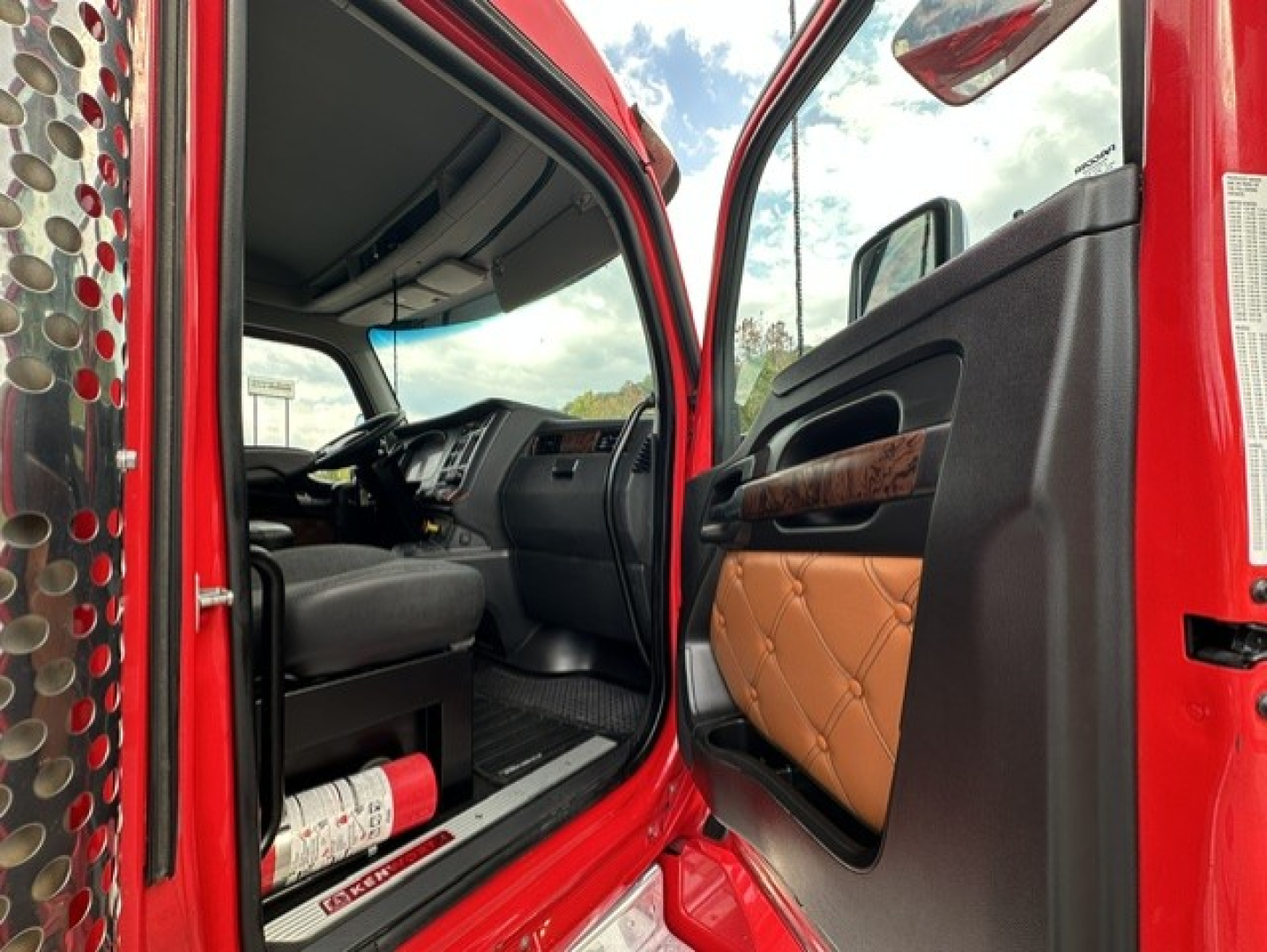 Kenworth T880 cab interior seen through open door; dashboard, steering wheel, and brown quilted door panel visible.