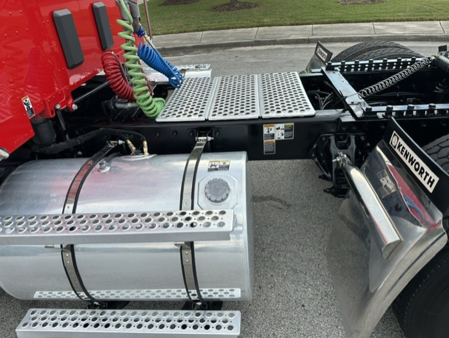 Side view showing Kenworth T880 fuel tank with perforated steps, rear cab area, coiled air lines, and chassis catwalk.
