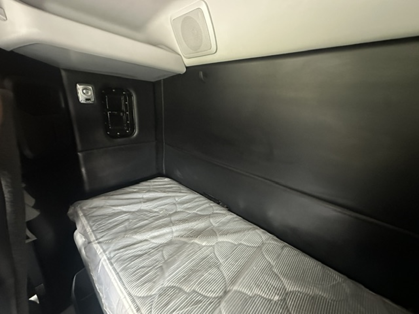 Kenworth T880 sleeper cab interior showing side wall and bunk with quilted mattress, electrical outlet panel, and storage area.