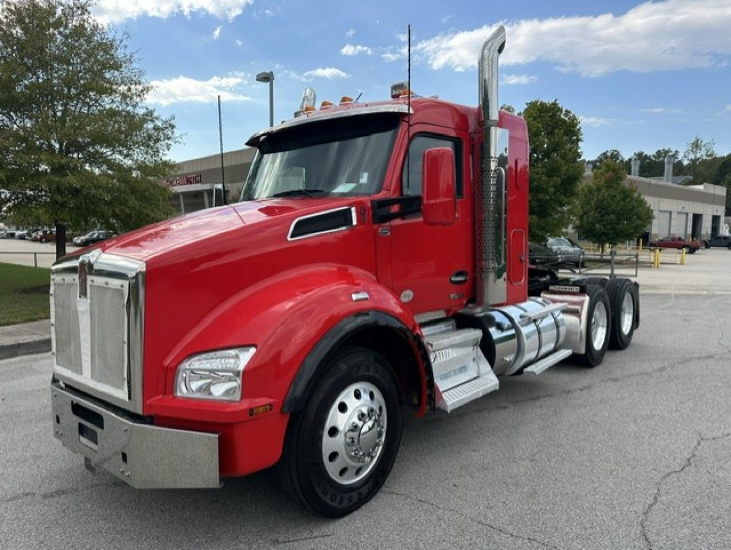 Kenworth T880 conventional sleeper truck in red from front-side angle showing chrome bumper and fuel tanks.