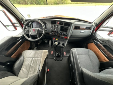 Kenworth T880 cab interior showing steering wheel, dashboard, gear shifter, and front seats.