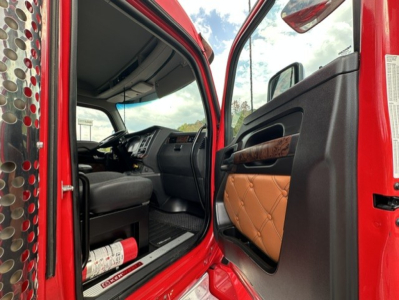 Kenworth T880 cab interior seen through open door; dashboard, steering wheel, and brown quilted door panel visible.
