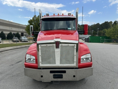 Kenworth T880 front view showing chrome grille, large bumper, dual vertical exhaust stacks, red cab, and daylight with clear sky.