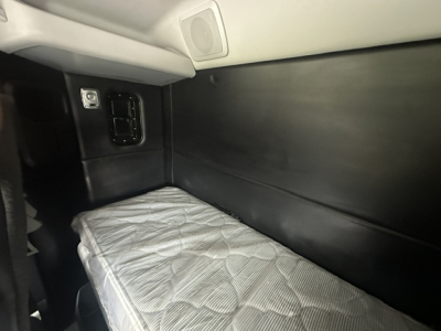 Kenworth T880 sleeper cab interior showing side wall and bunk with quilted mattress, electrical outlet panel, and storage area.