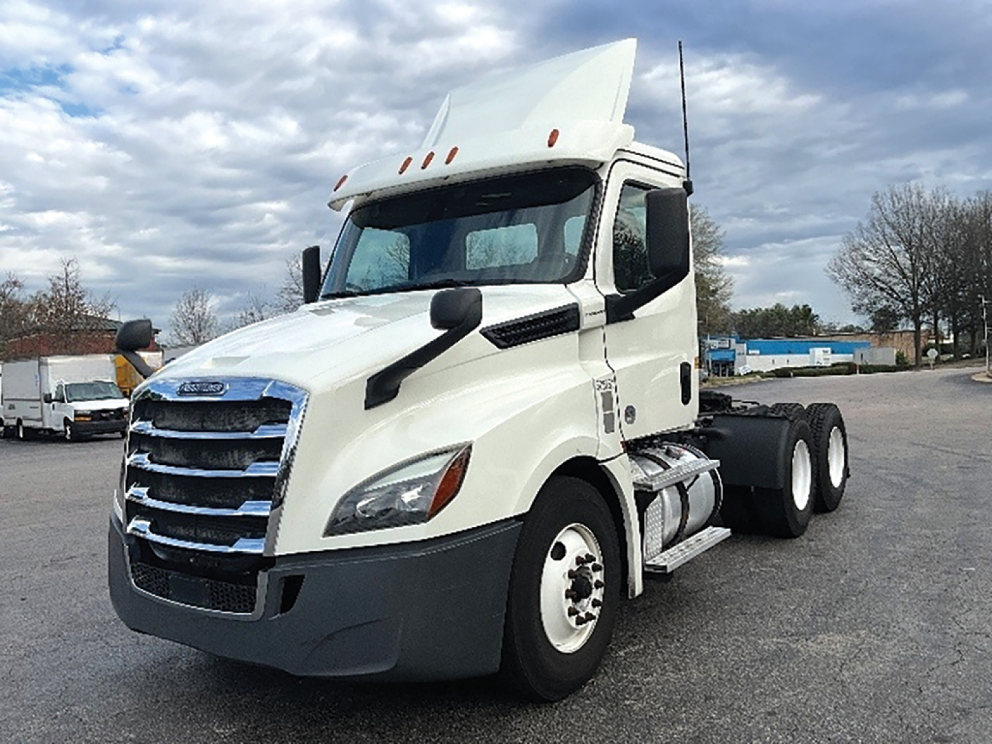 Front-left side view of a white Freightliner Cascadia126 day cab truck with raised sleeper, showing chrome grille, tall aerodynamic mirrors, and dual rear axles.