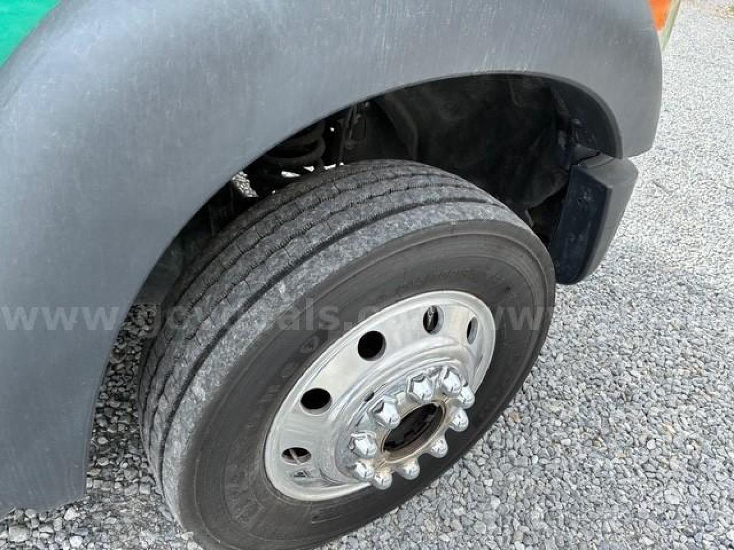 Front wheel and fender of a 2012 Ford F550 flatbed truck showing dual rear wheels, hub with lug nuts, and tire tread.