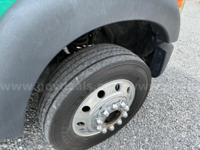 Front wheel and fender of a 2012 Ford F550 flatbed truck showing dual rear wheels, hub with lug nuts, and tire tread.