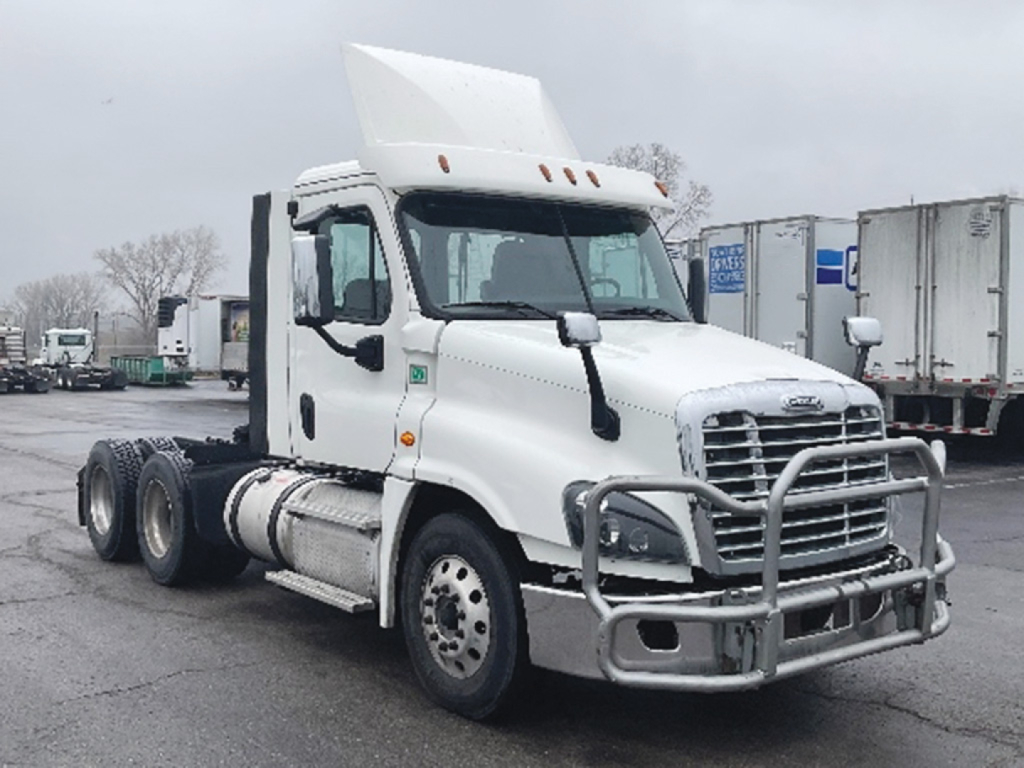 Truck cab showing Freightliner Cascadia125 daycab with chrome grille guard, white exterior, dual rear axles, and sleeperless cabin.