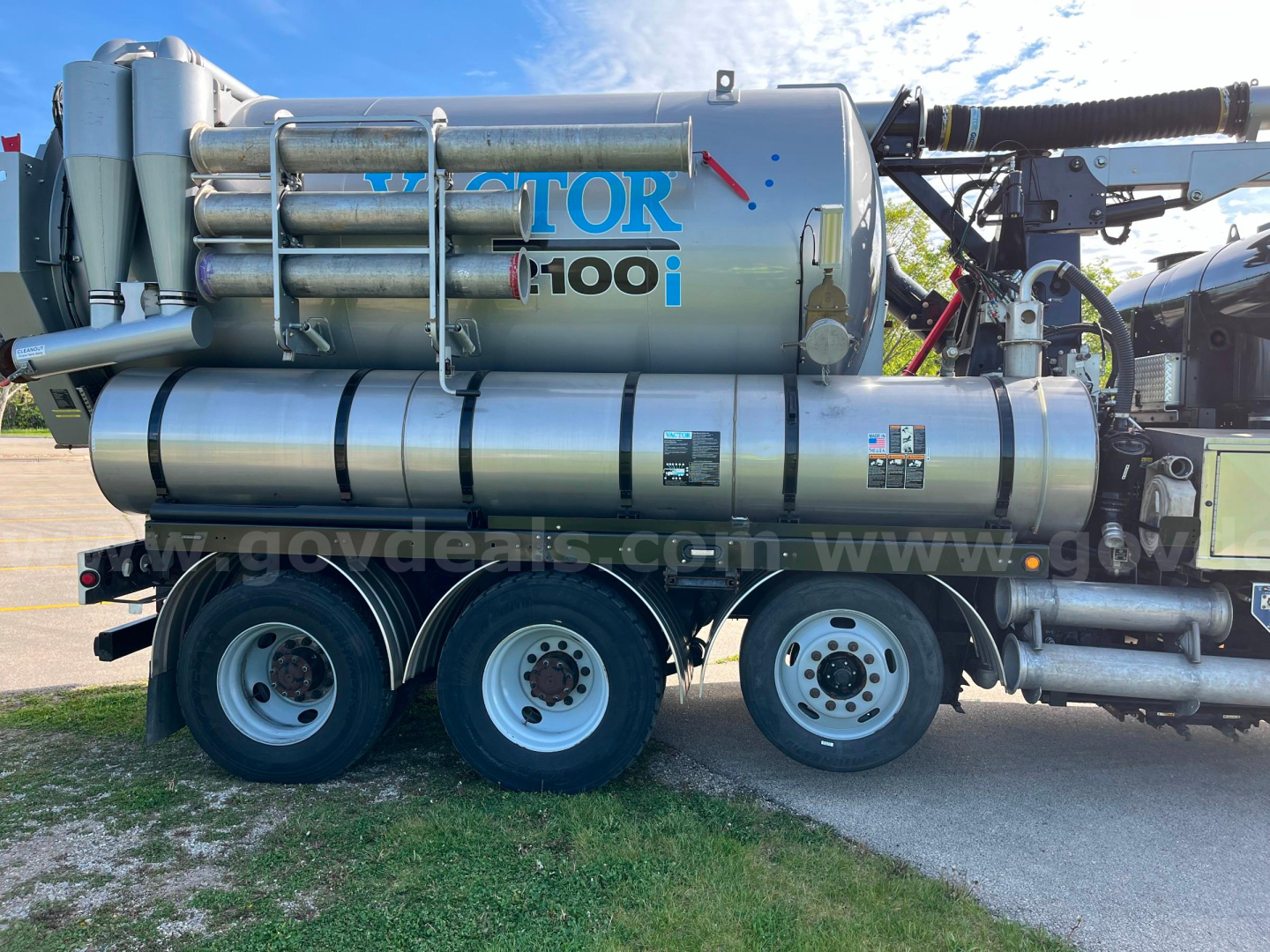 Truck-mounted Vactor 2100i sewer jetting system on a three-axle trailer showing large stainless tank with VACTOR 100i branding and hoses.
