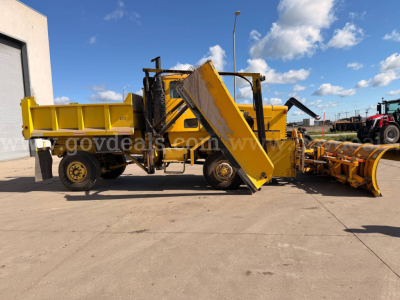 Oshkosh PA-2523-3 plow truck with front-mounted conveyor and yellow equipment, side view showing hydraulic lift and plow attachment.
