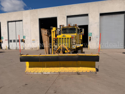 Oshkosh PA-2523-3 snow plow truck with large yellow blade in front, yellow cab, storage bays in background.