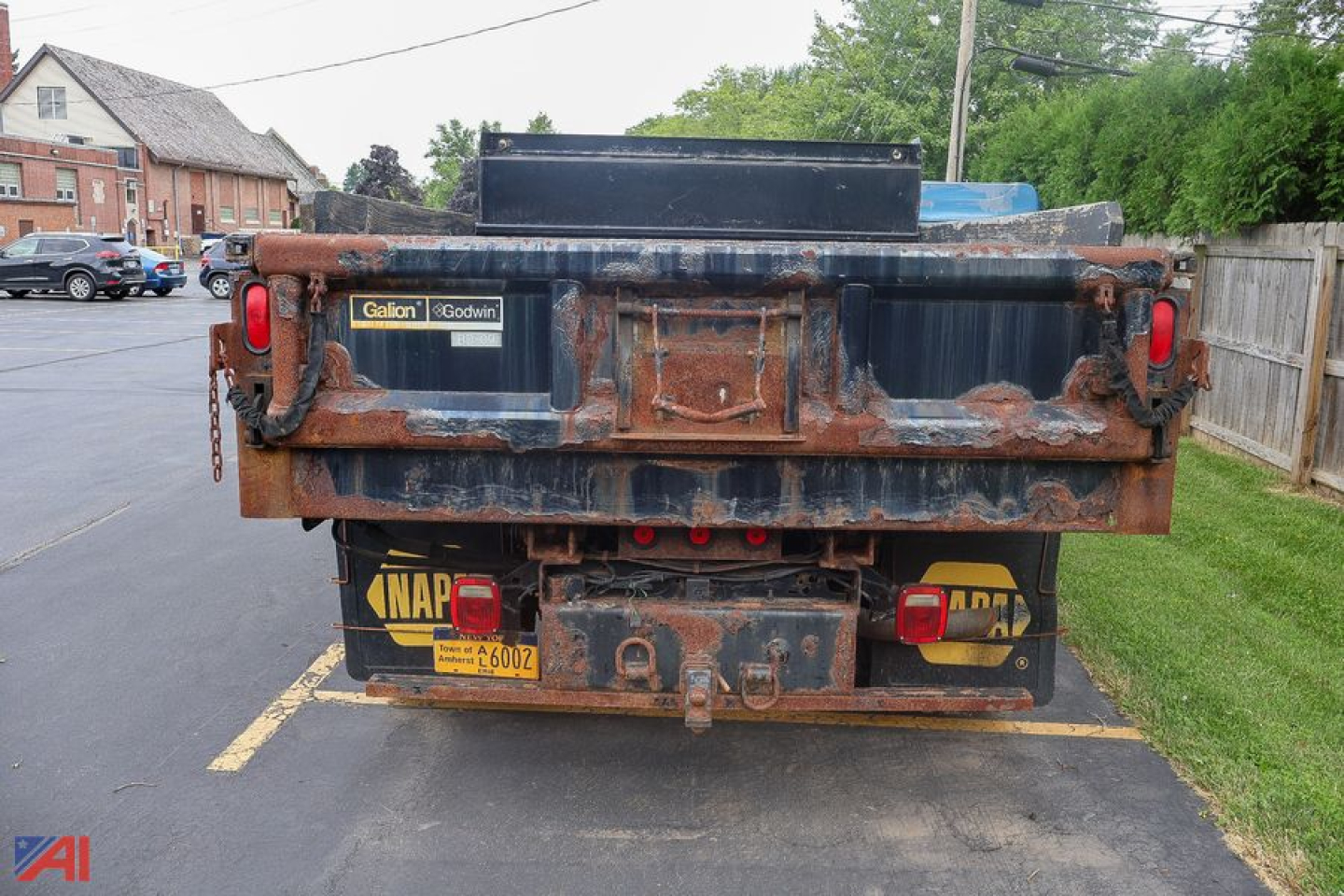 Ford F-350 Super Duty dump truck rear view with rusted bed and plow, yellow NAPA license plates, and dual rear red lights.