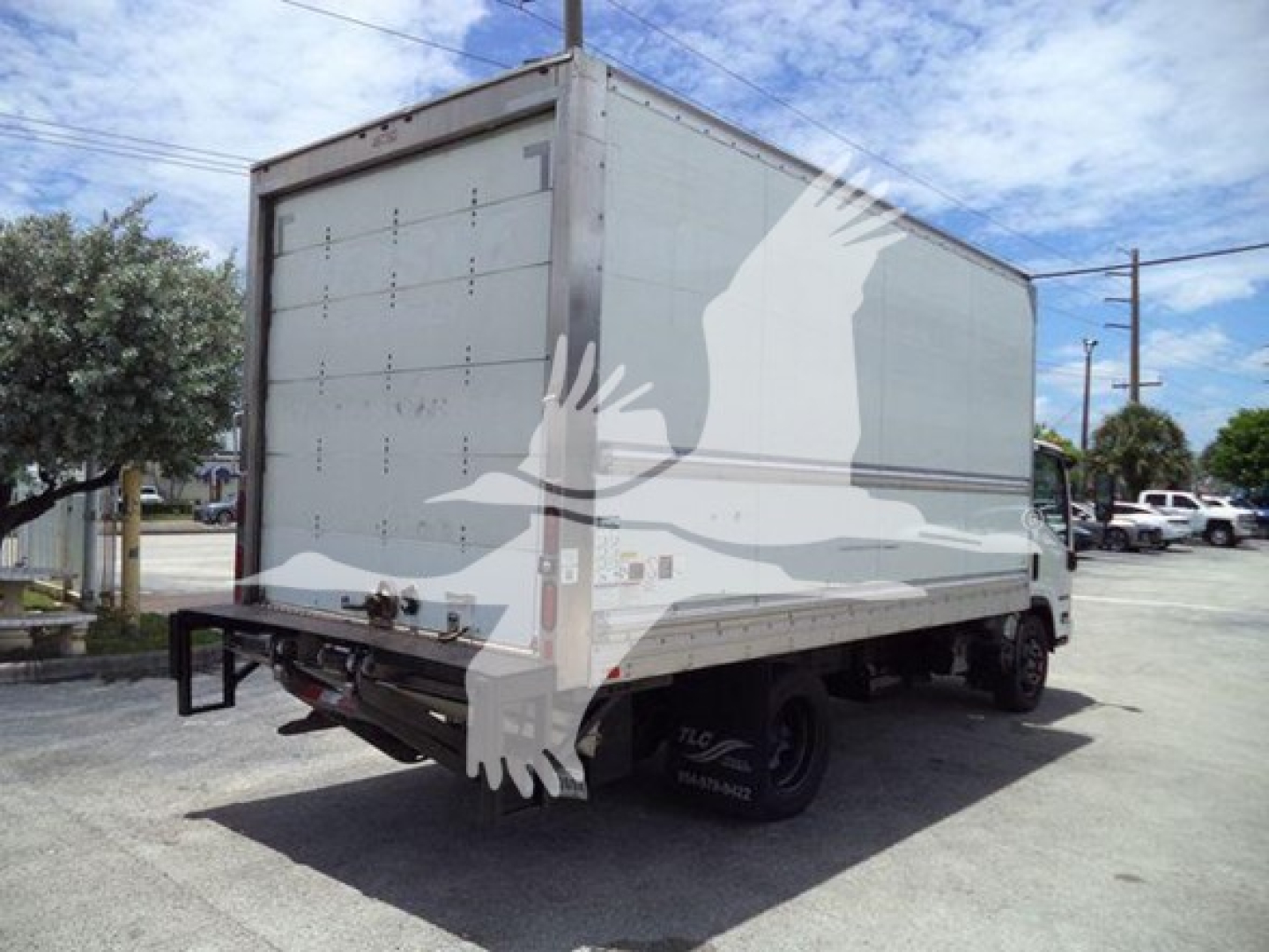 Isuzu NPR HD box truck rear-left angle showing back doors and tail, with stock and VIN info not visible on vehicle; no visible text readable on side panels.