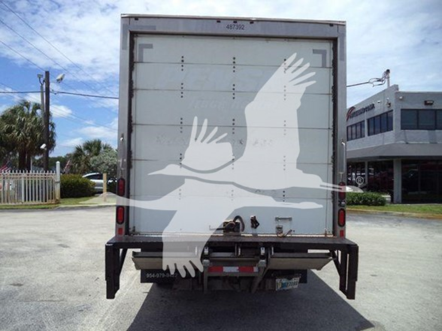 Isuzu NPR HD box truck rear view showing white graphic on rear doors and taillights.