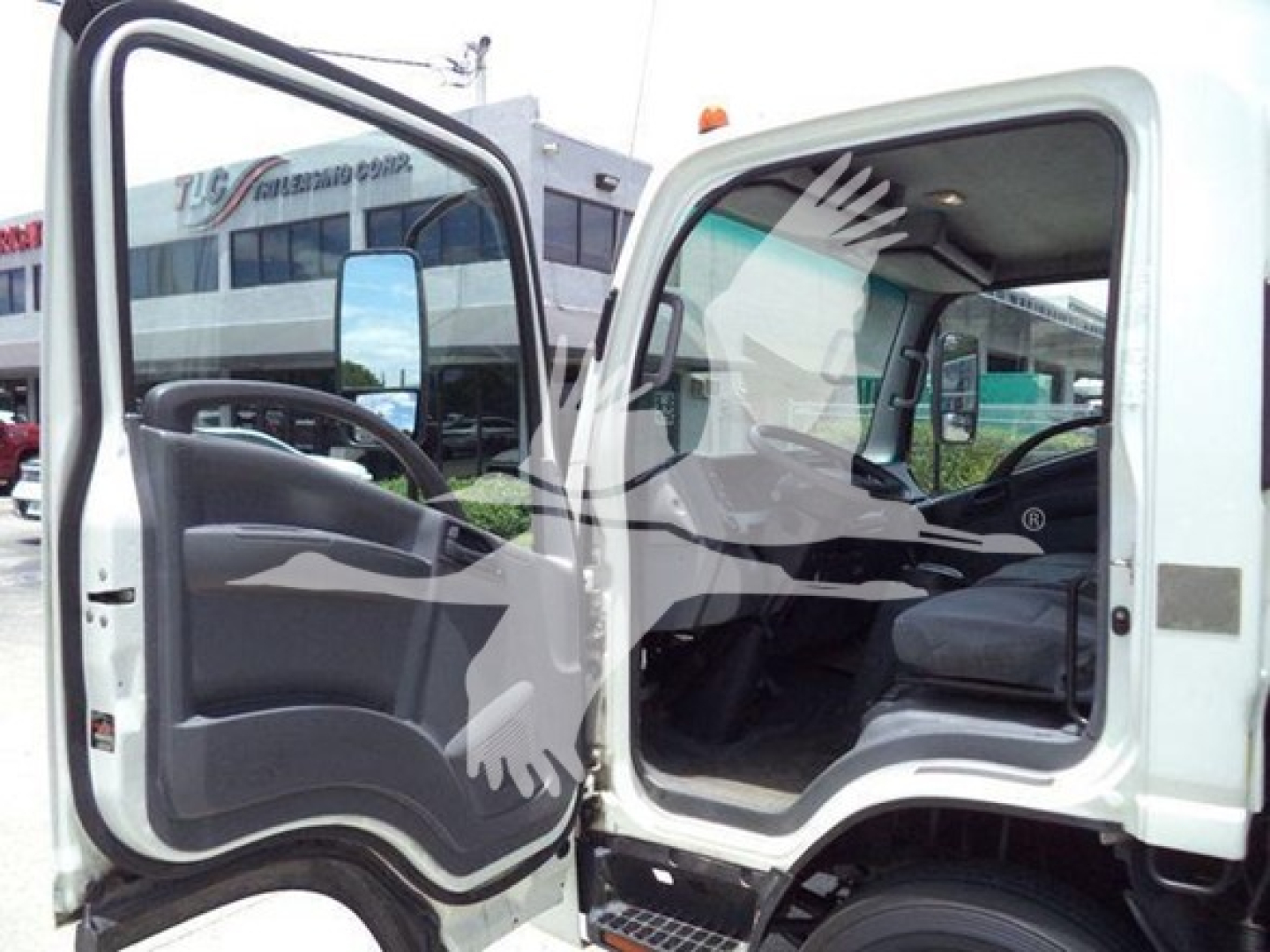 Isuzu NPR HD truck cab interior and open driver and passenger doors, showing steering wheel, seat, and dashboard from the exterior.