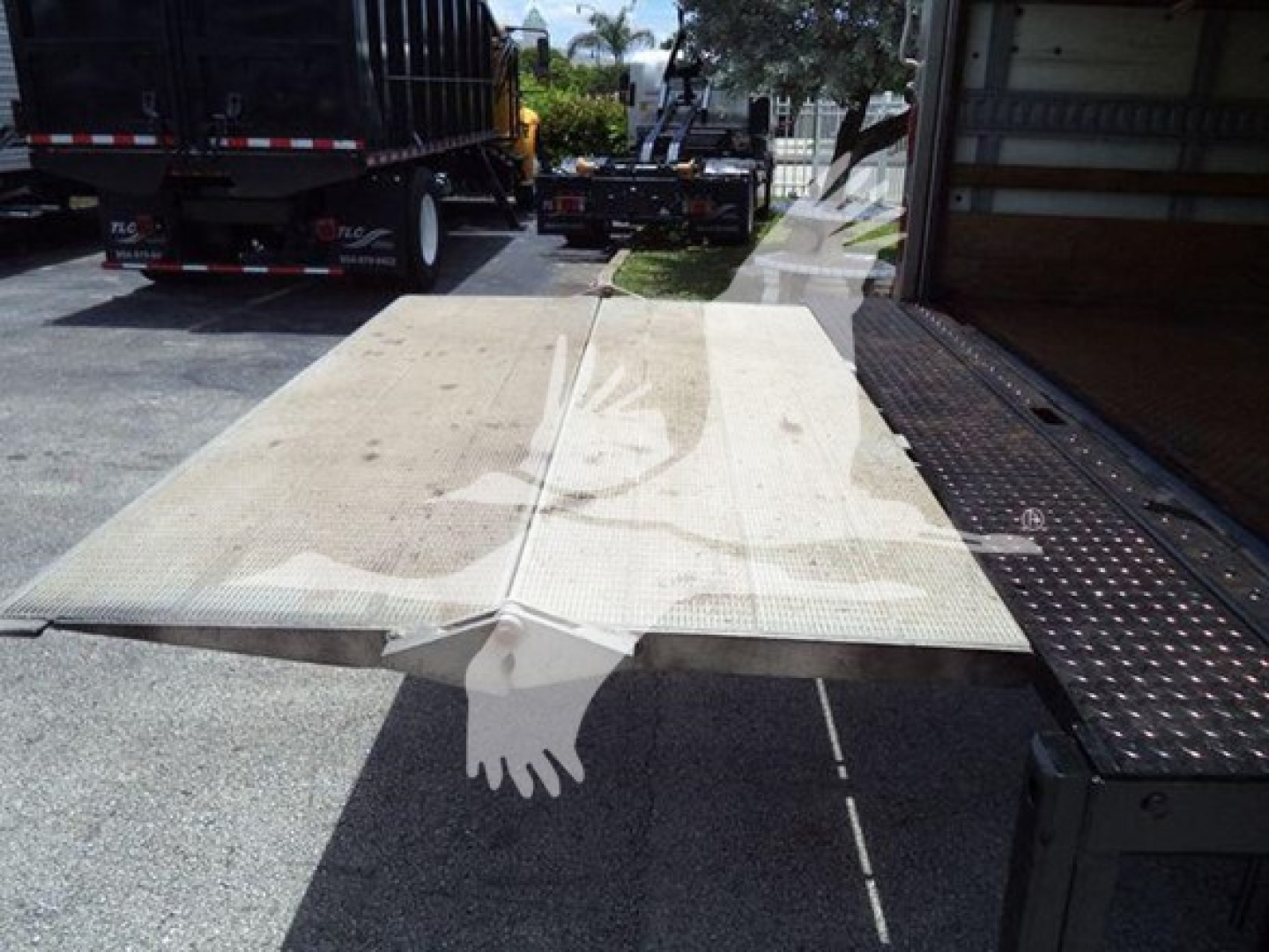 Isuzu NPR HD box truck rear view showing a flatbed or loading ramp attached to a side utility platform.