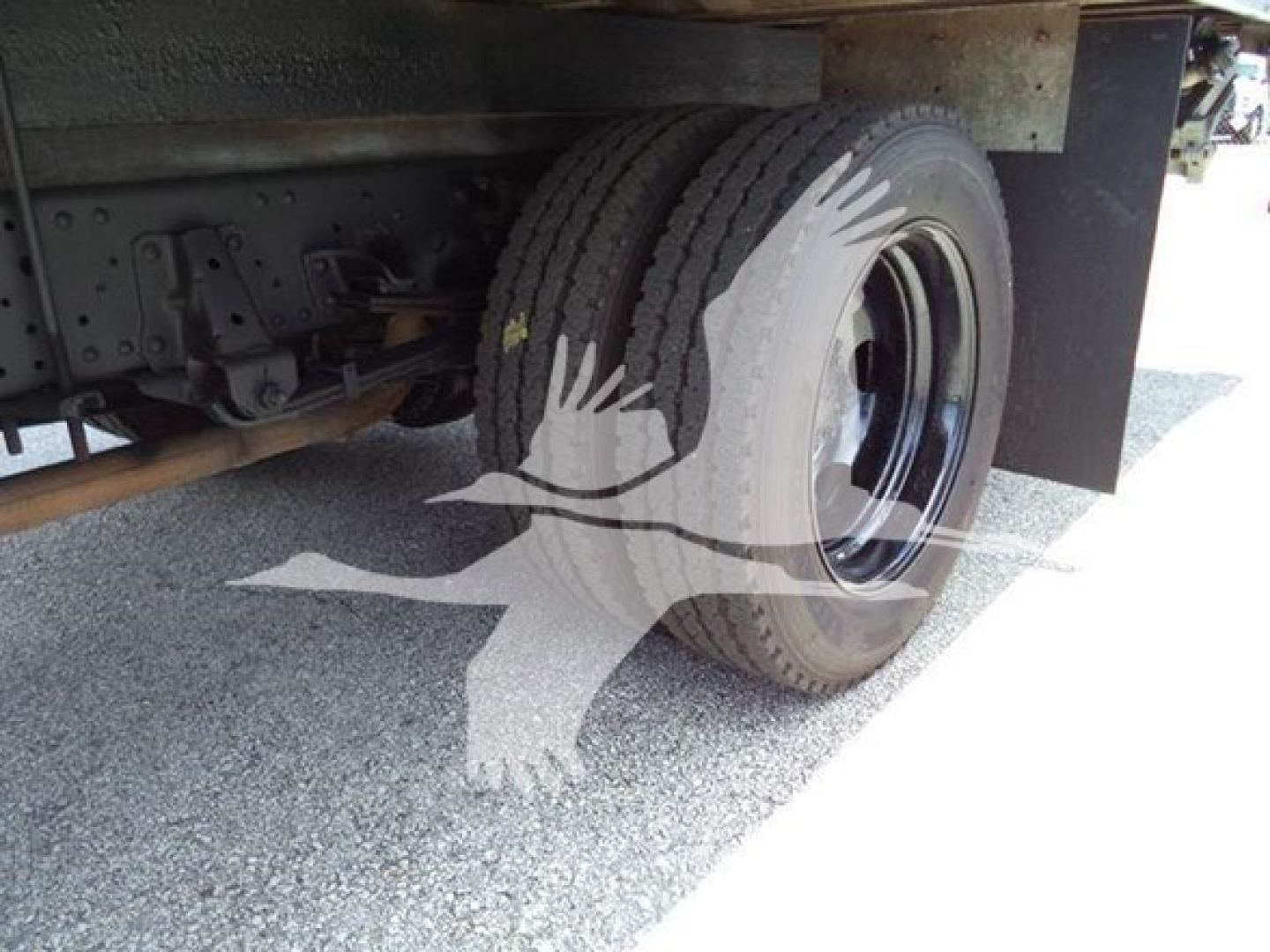 Isuzu NPR HD truck rear wheel area showing dual rear tires and undercarriage components.
