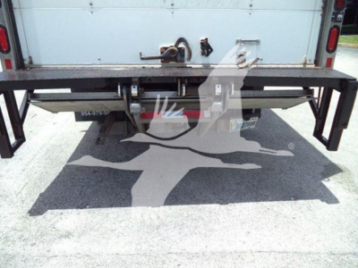 Isuzu NPR HD truck rear with a fold-out metal platform/bumper and toolbox; visible text includes '954-979-?' on left, and some stickers and cables under the platform.