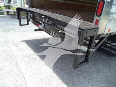 Isuzu NPR HD box truck rear showing a black heavy-duty fold-down ramp and rear bumper with reflective markings.