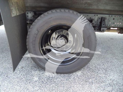 Isuzu NPR HD truck wheel and undercarriage view; spare tire mounted under cargo area with black steel rim.