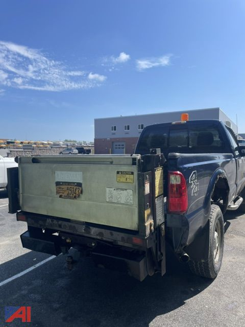 Ford F-350 Super Duty pickup truck with plow and lift gate, rear view showing dump bed and tow hitch.