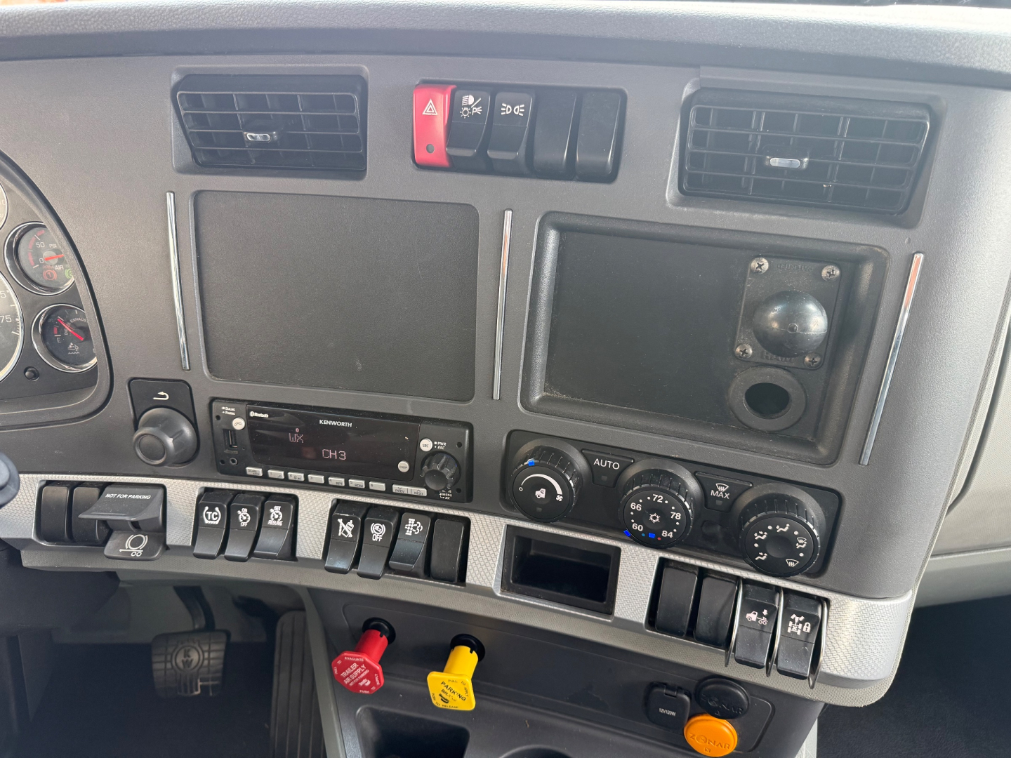 Kenworth T680 dashboard panel showing various switches and gauges, cab controls, and climate dials.