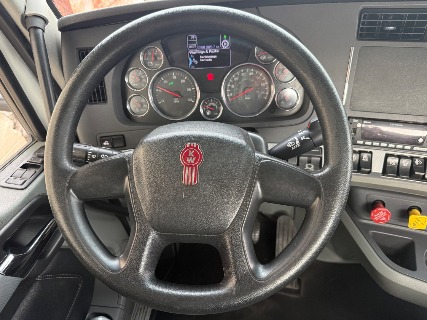 Kenworth T680 dashboard and steering wheel view showing instrument cluster, steering wheel with KW emblem, center console controls, and gauge faces.