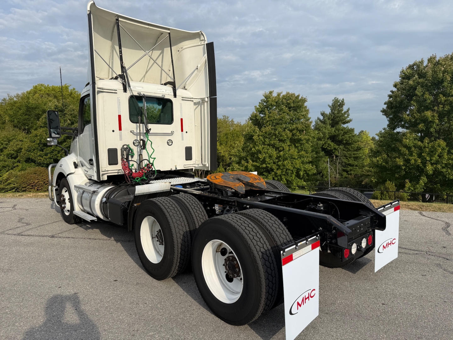 Kenworth T680 tractor chassis rear view showing dual rear axles and seventh-wheel with white rims and MHC mud flaps.