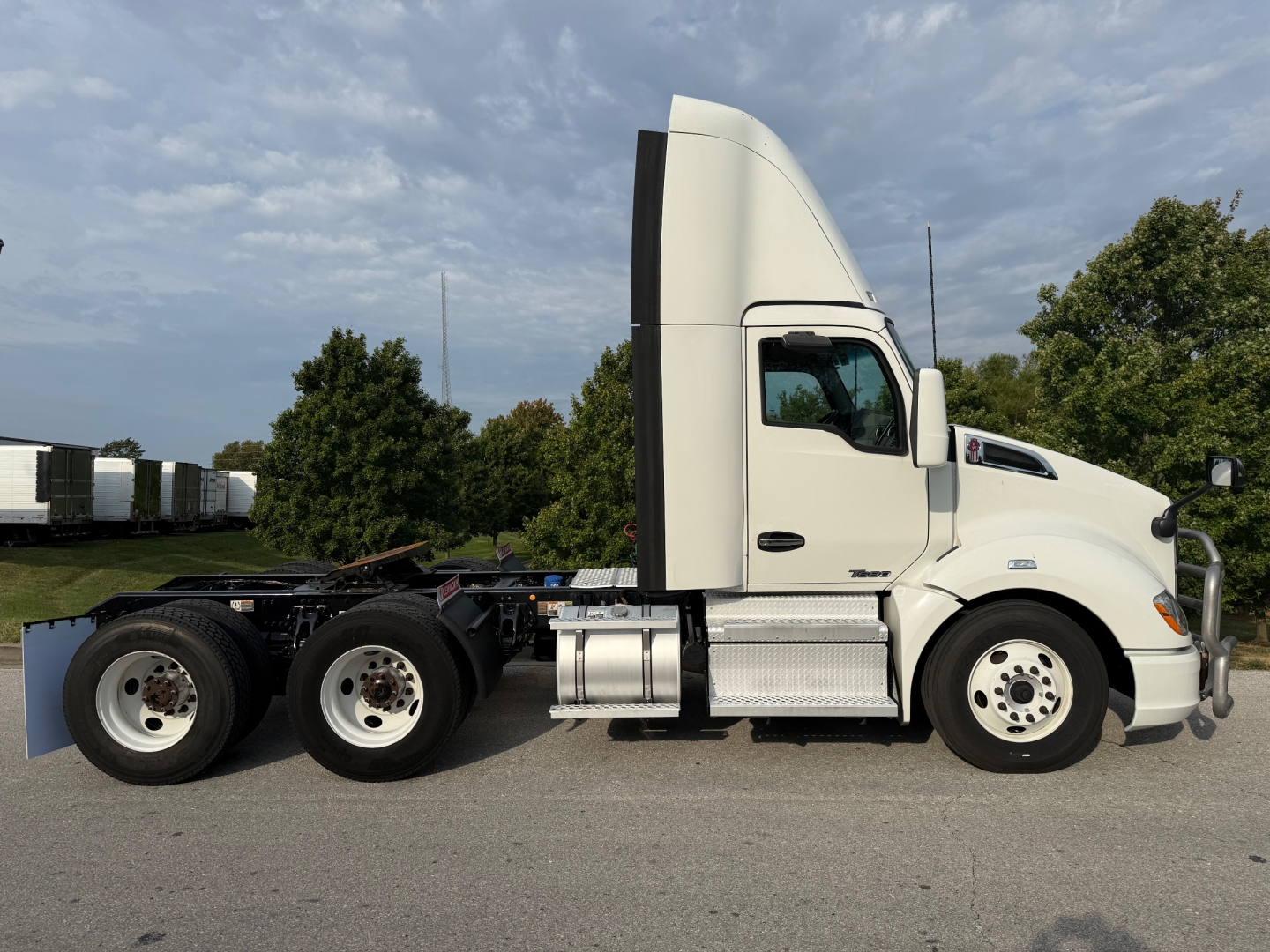 Kenworth T680 tractor side view showing sleeper cab, dual rear axles, and aluminum fuel tanks.